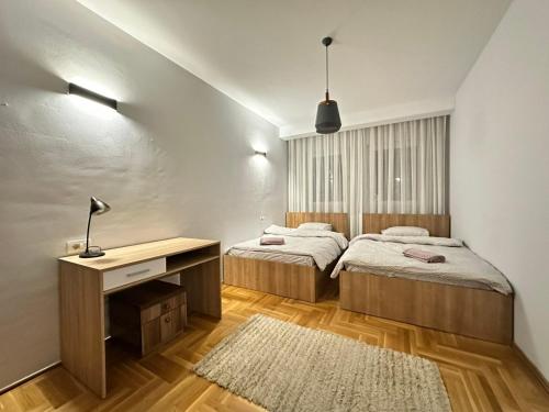 a bedroom with two beds and a desk and a rug at Large Apartment in Pristina