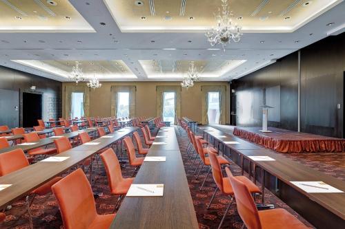 a large room with long tables and orange chairs at Grand Hotel River Park, a Luxury Collection Hotel, Bratislava in Bratislava