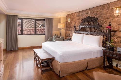 a bedroom with a large bed and a stone wall at JW Marriott El Convento Cusco in Cusco