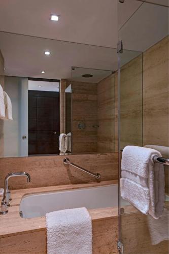 a bathroom with a tub and a glass shower at JW Marriott El Convento Cusco in Cusco