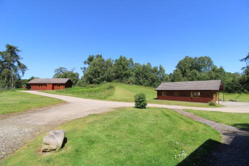 a dirt road next to a building and a house at Plodda Lodge at Lochletter Lodges in Drumnadrochit