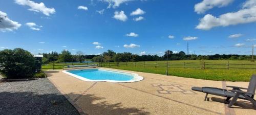 - une piscine avec un banc à côté d'un champ dans l'établissement Maison de campagne, 17 couchages, à Tresson