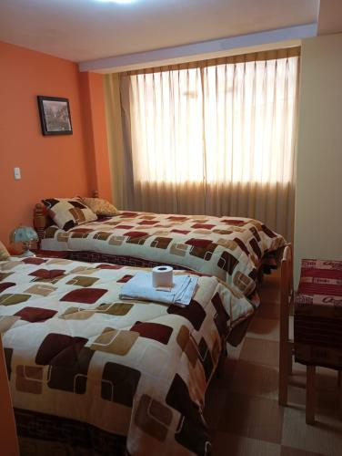 a bedroom with two beds and a window at Hostal Vista al Lago Titicaca Puno in Puno