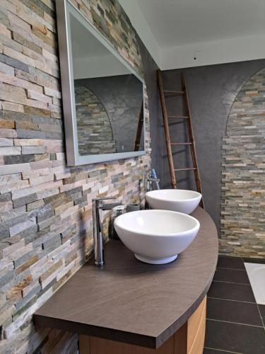 La salle de bains est pourvue de 2 lavabos et d'un mur en briques. dans l'établissement Maison de campagne, 17 couchages, à Tresson