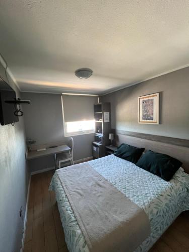 a bedroom with a bed and a desk and a window at Hotel Aranjuez in Chillán