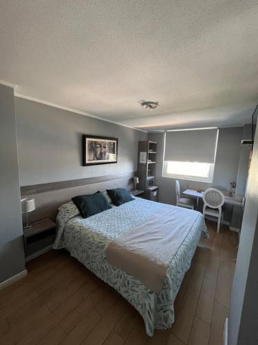 a bedroom with a large bed and a desk at Hotel Aranjuez in Chillán