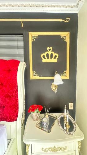 a bedroom with a bed with a table with a crown on the wall at House of Royalty in Gqeberha