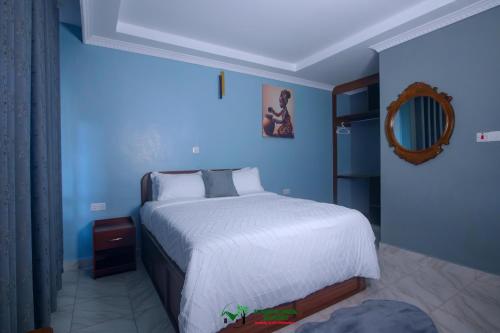 a blue bedroom with a bed and a mirror at Juniper Park Resort in Nyahururu