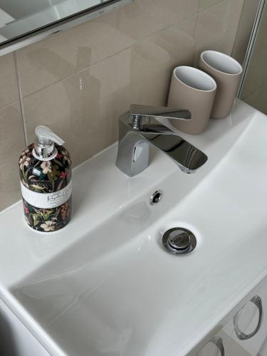 a bathroom sink with a faucet and cups on it at Stylish & spacious home in the Chilterns in Chinnor