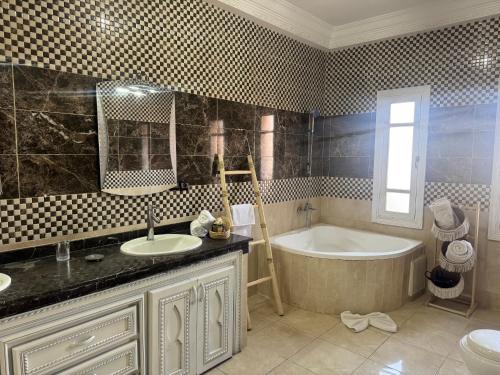マラケシュにあるMaison Jannate Louiseの浴槽と洗面台とバスタブを備えたバスルーム