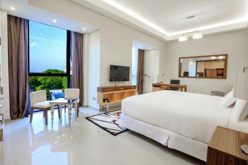a white bedroom with a large bed and a television at Element by Westin Hotel Dar es Salaam in Dar es Salaam