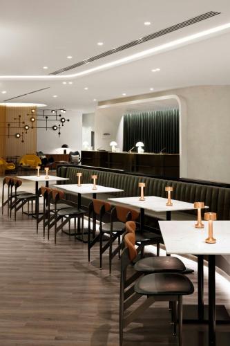 a dining room with white tables and chairs at Le Meridien Melbourne in Melbourne