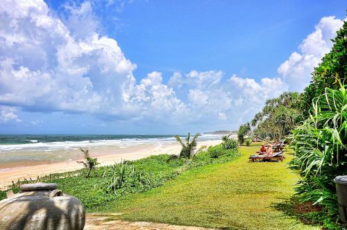 a path to the beach with people sitting on a bench at The Long Beach Resort & Spa in Koggala