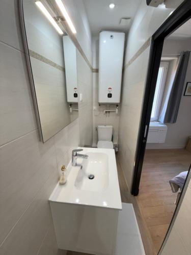 une salle de bain blanche avec un lavabo et un miroir dans l'établissement Appartement cozy et hyper centre, à Menton