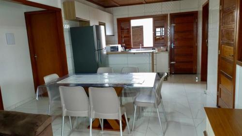 a kitchen with a table and chairs and a refrigerator at Casa pé na areia in Balneário Gaivotas