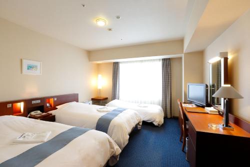 a hotel room with two beds and a television at Keisei Hotel Miramare in Chiba
