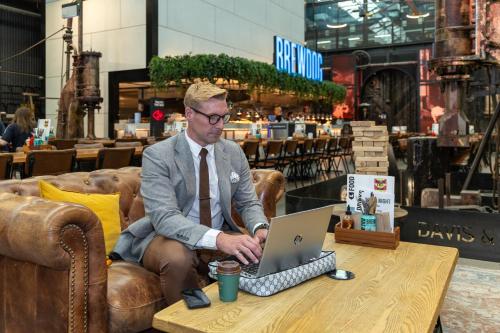a man sitting in a chair with a laptop on a table at Hoteloco in Sydney