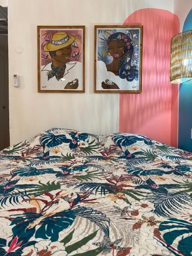 een slaapkamer met een bed met drie foto's aan de muur bij Bienvenue au Ti Frangipanier in Saint-François