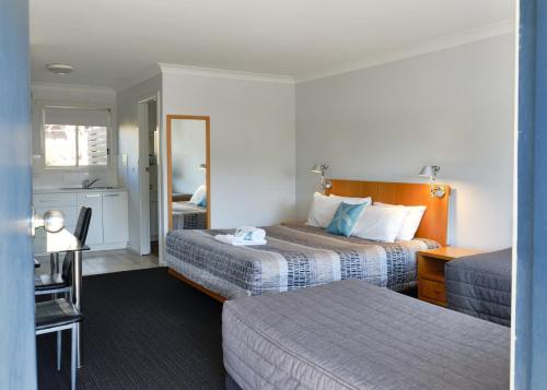 a hotel room with two beds and a mirror at Culburra Beach Motel in Culburra Beach