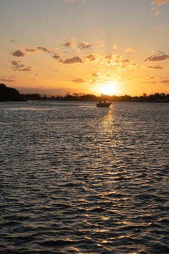 a boat on a body of water with a sunset at Culburra Beach Motel in Culburra Beach