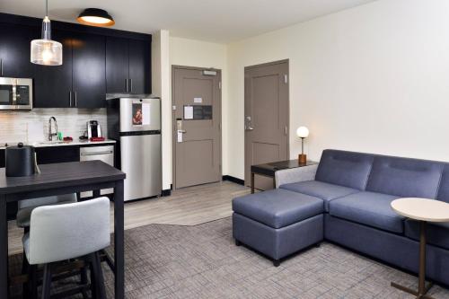 a living room with a blue couch and a kitchen at Residence Inn by Marriott Bakersfield West in Bakersfield