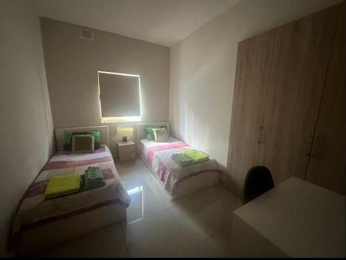 a room with two beds and a table and a mirror at Central Stay Malta - Rooms in Tal-Ħriereb