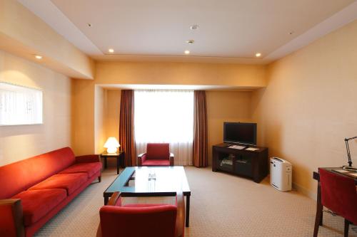 a living room with a red couch and a tv at Keisei Hotel Miramare in Chiba