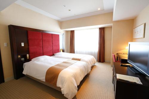a hotel room with a large bed and a flat screen tv at Keisei Hotel Miramare in Chiba