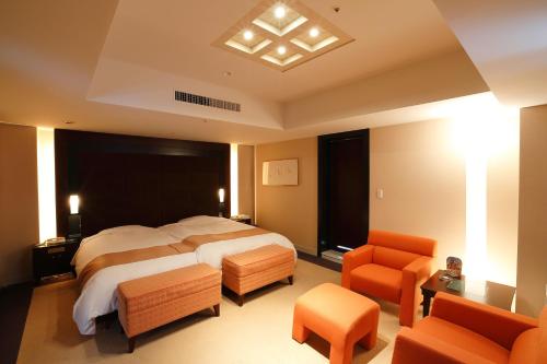 a bedroom with a large bed and orange chairs at Keisei Hotel Miramare in Chiba