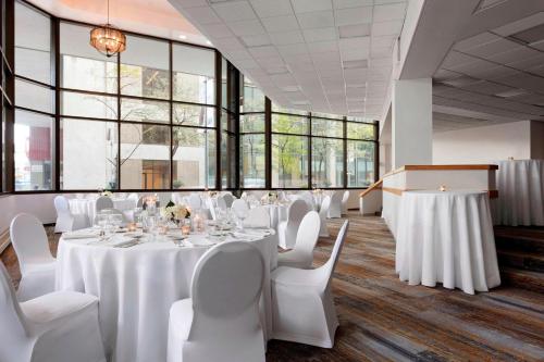 a room with white tables and chairs and windows at Des Moines Marriott Downtown in Des Moines