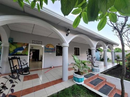 a building with white columns and a porch with plants at Ometepe House in Moyogalpa