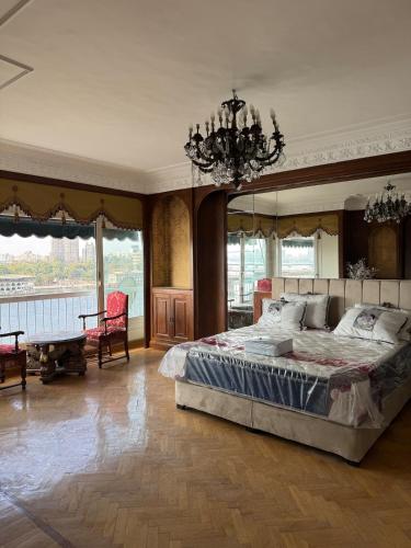 a bedroom with a large bed and a chandelier at Prestigious Nilefront Luxury in Cairo