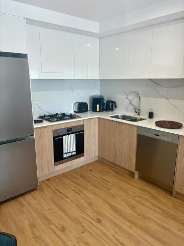 a kitchen with white cabinets and a stove and a sink at Chermside Central Apartment in Brisbane