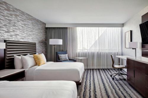 a hotel room with two beds and a desk at Ventura Beach Marriott in Ventura