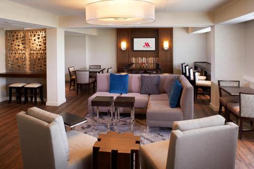 a living room with a couch and tables and chairs at Detroit Metro Airport Marriott in Romulus