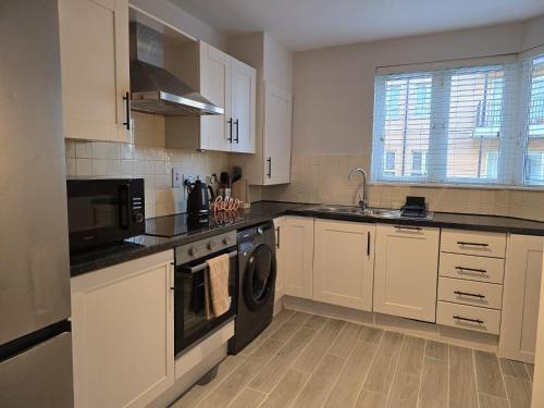 a kitchen with white cabinets and a washer and dryer at Dublin - 3 Bedroom Cosy Home - Sleeps Max 7 in Dublin