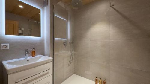 a bathroom with a shower and a sink and a mirror at Daphné Heights by Villars Luxury in Villars-sur-Ollon
