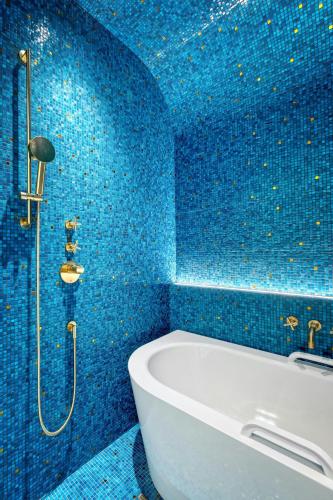 a blue bathroom with a tub and blue tiles at Matild Palace, a Luxury Collection Hotel in Budapest