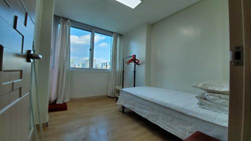 a white room with a bed and a large window at Namsan Ville in Seoul