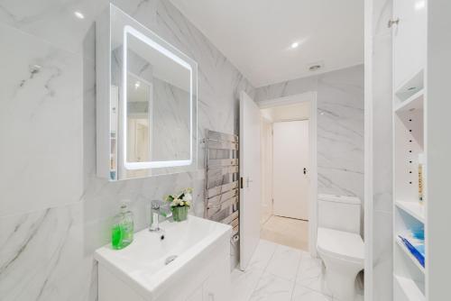 a white bathroom with a sink and a mirror at Cosy Charming Apartment in Central London in London