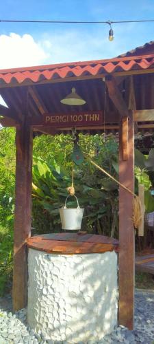 a pergola with a pot on top of a stone pillar at Bagas Zakariah Orchard Lodge in Gopeng
