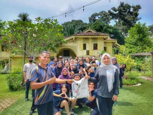 a group of people posing for a picture in front of a house at Bagas Zakariah Orchard Lodge in Gopeng