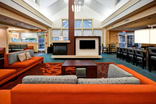 a lobby with orange furniture and a flat screen tv at Residence Inn by Marriott Springfield Chicopee in Chicopee