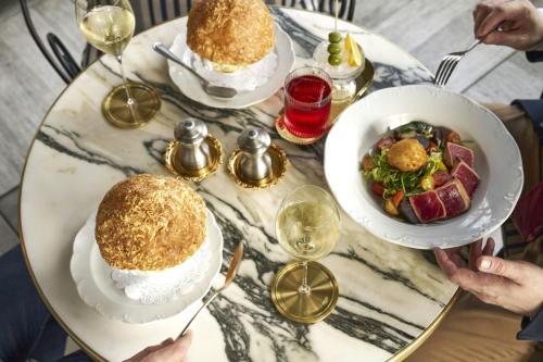 a table with two plates of food and glasses of wine at Le Meridien New York, Central Park in New York