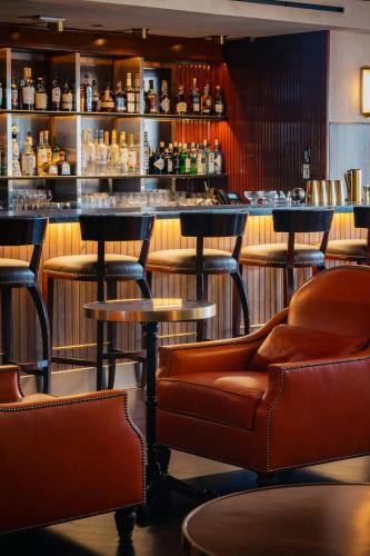 a bar with brown leather chairs and a counter at Le Meridien New York, Central Park in New York