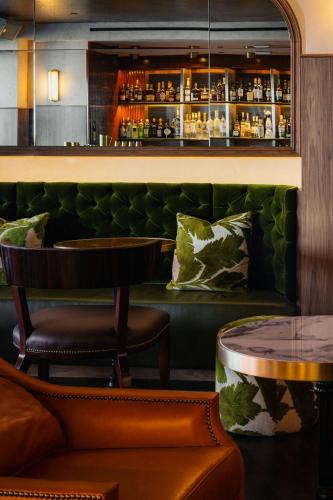 a bar with two chairs and a green couch at Le Meridien New York, Central Park in New York