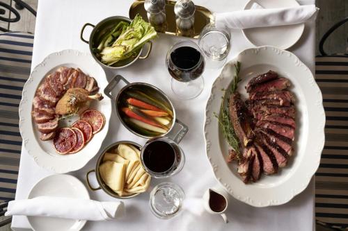 a white table with plates of food and glasses of wine at Le Meridien New York, Central Park in New York