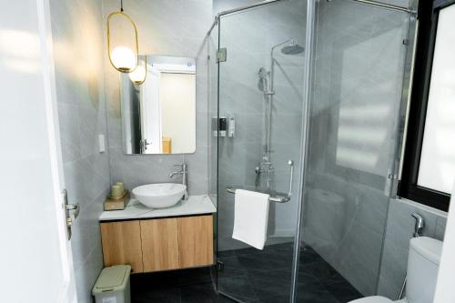 a bathroom with a sink and a glass shower at TN Hue Dorm in Hue