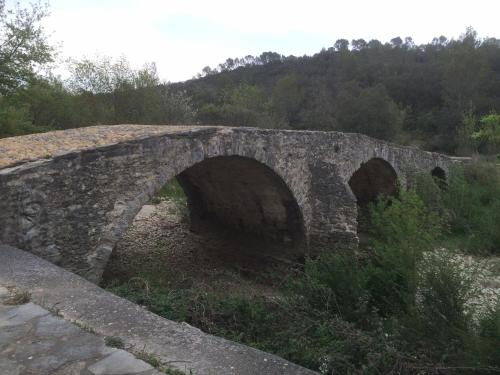 an old stone bridge with three arches on a hill at B&B Le Mas Des Chenes in Vacquières