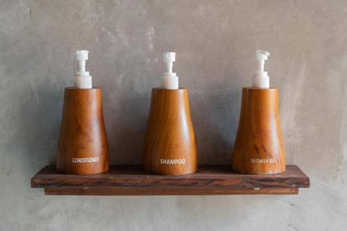 three brown bottles sitting on a wooden shelf at Harmony Wooden Villas in Ubud